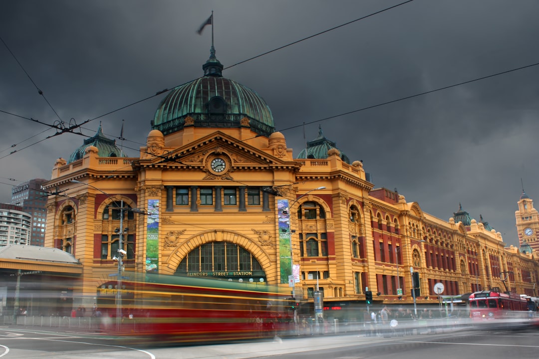 time-lapse photography of vehicles passing by the brown and green building structure under gray clouds